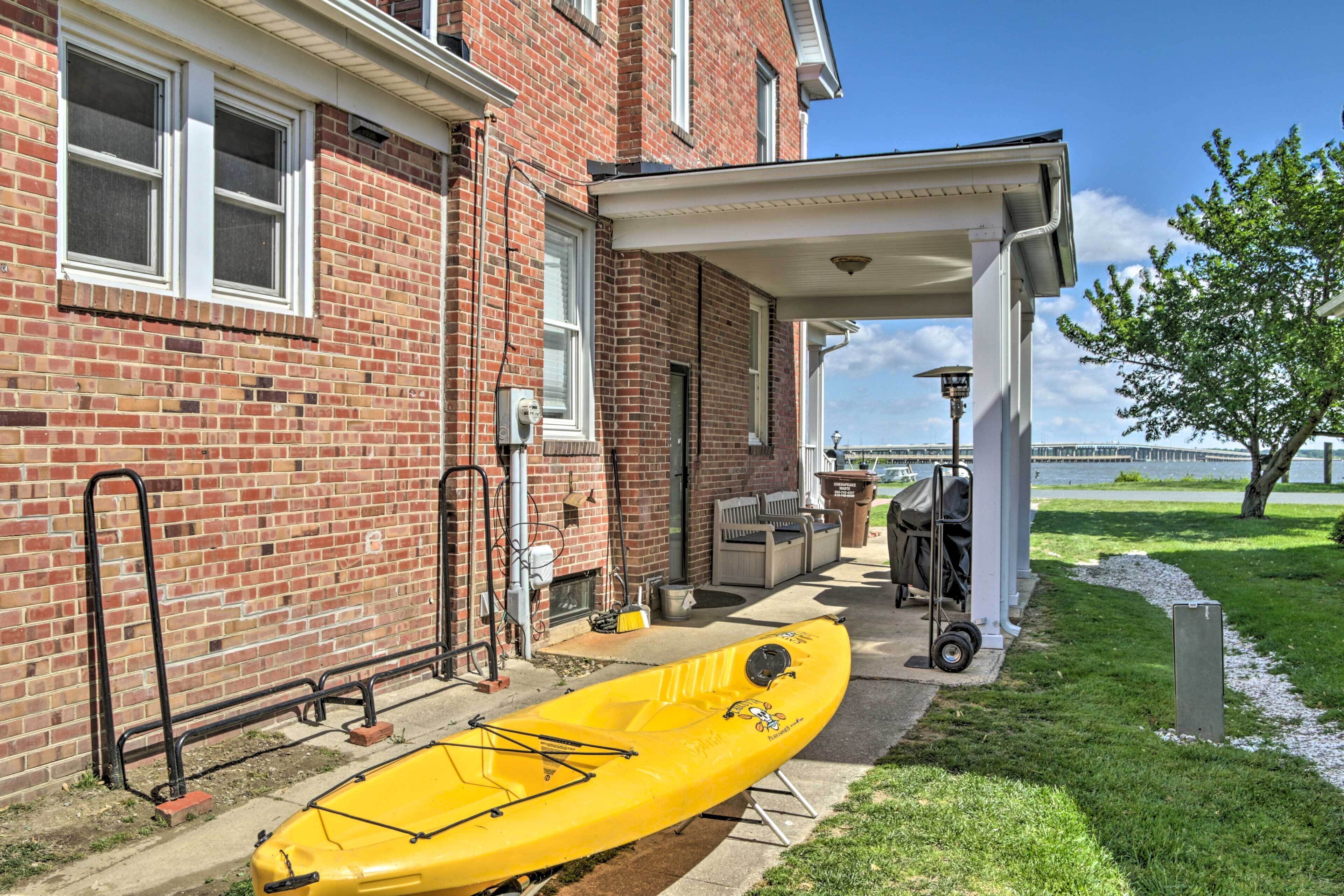 A brick building with a covered patio, a kayak, and outdoor furniture.