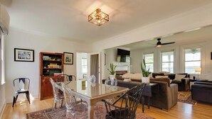 A spacious living room with a glass dining table, wooden chairs, a fireplace, and a large window. - Beautiful Colonial Home on the Choptank River (Cambridge)