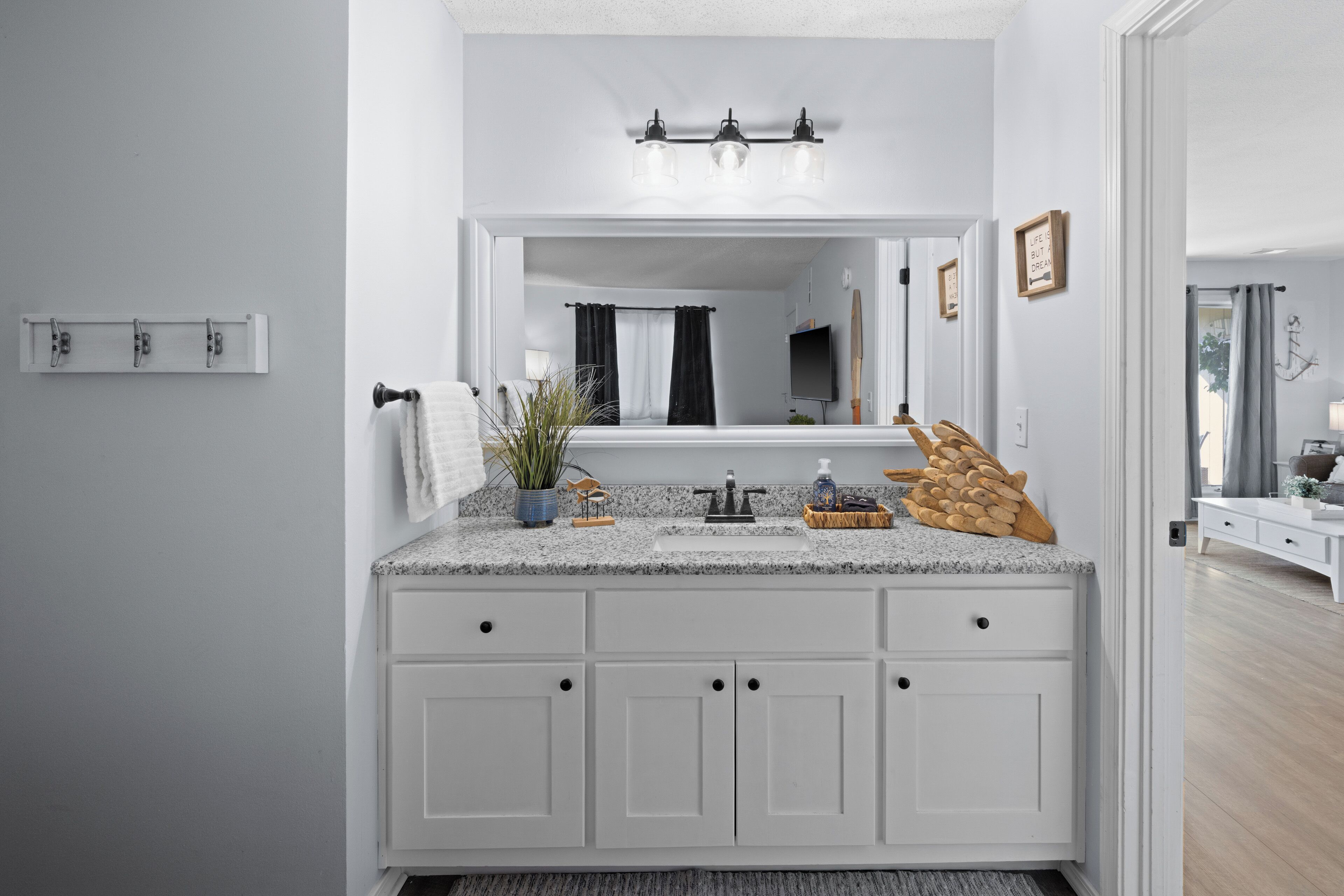 A bathroom with a white vanity, a mirror, a sink, and a towel rack.