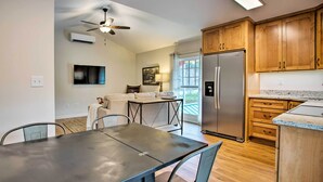 Una cocina moderna con armarios de madera, un refrigerador de acero inoxidable y un comedor con mesa y sillas.