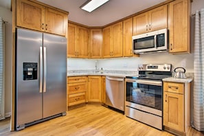 A modern kitchen with wooden cabinets, stainless steel appliances, and a granite countertop.