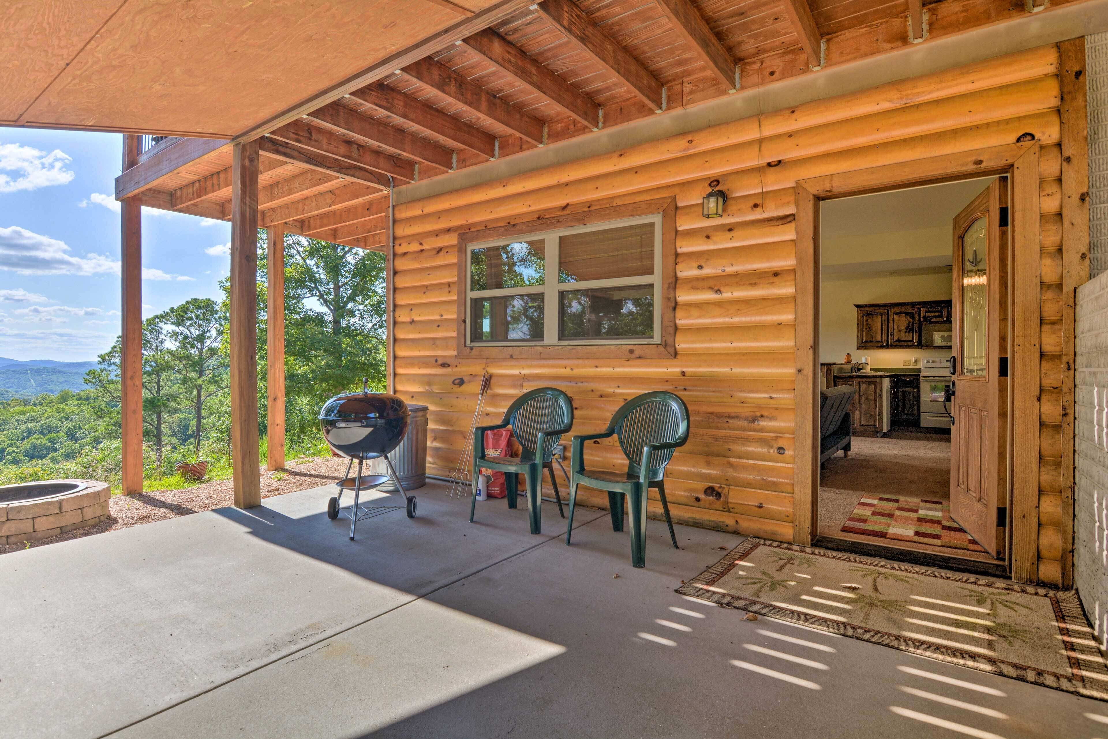A wooden cabin with a covered patio, a barbecue grill, and two chairs.