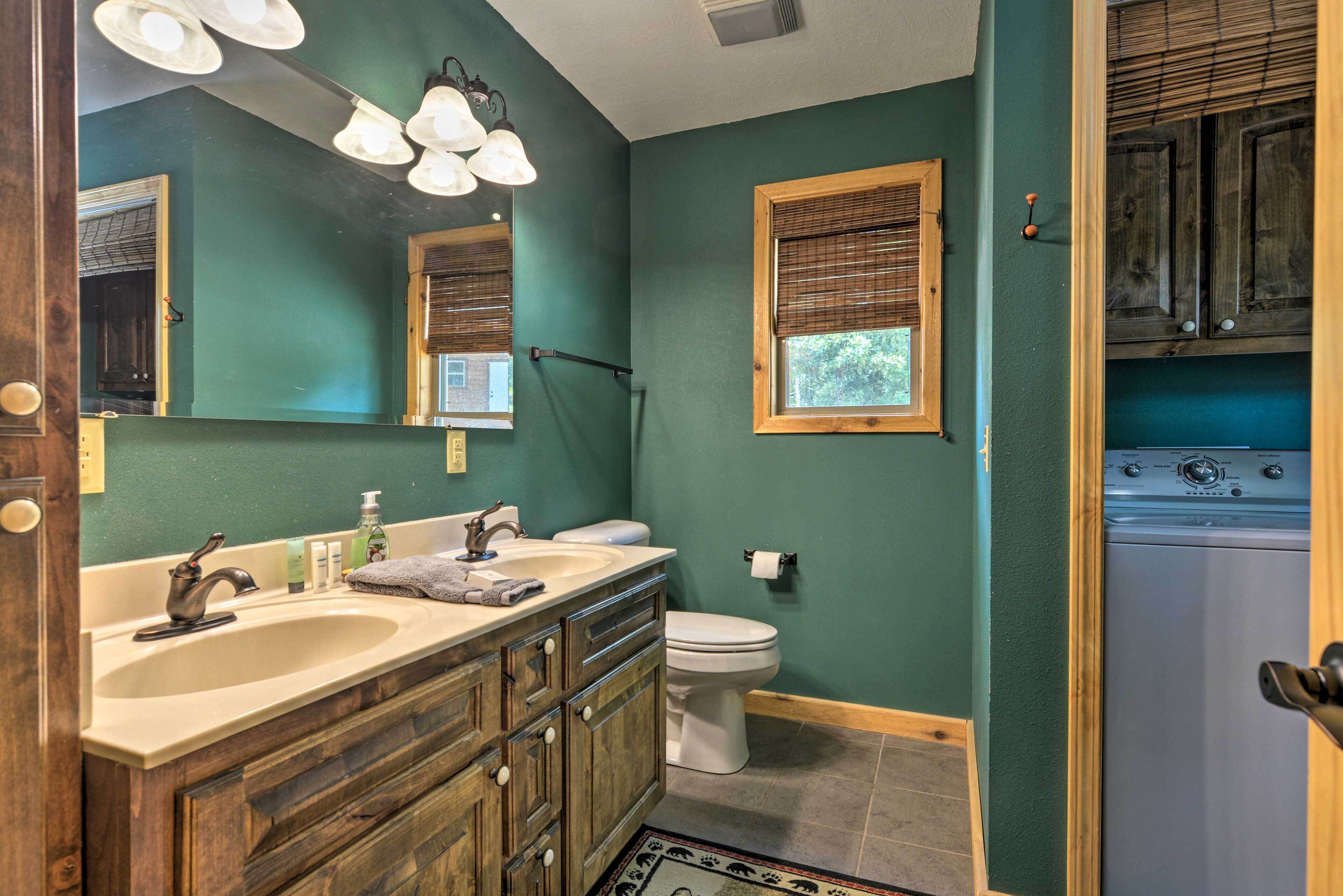 A bathroom with a wooden vanity, a sink, a toilet, and a washing machine.