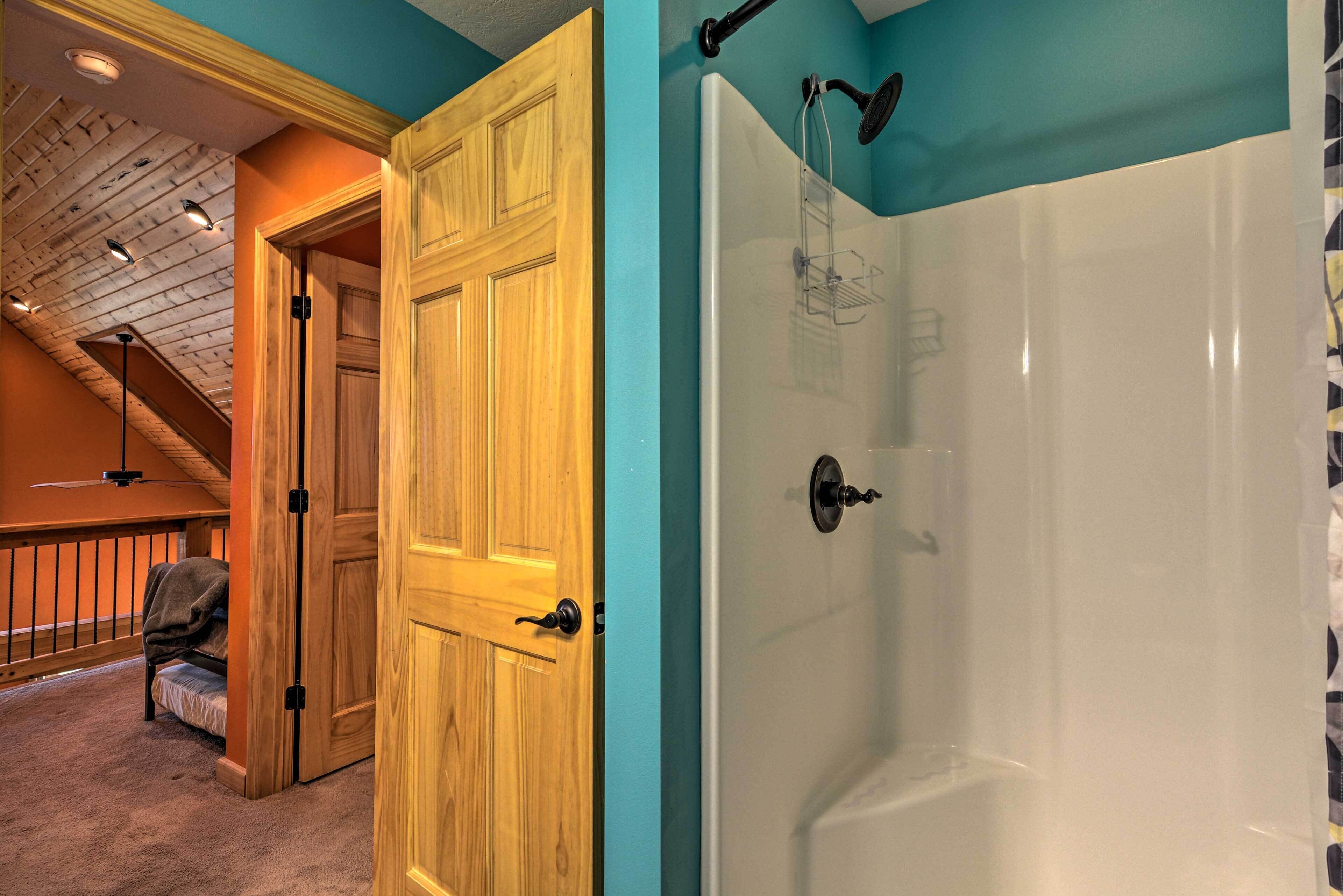 Una habitación con puerta de madera, una bañera blanca y un ventilador de techo.