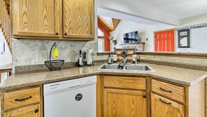 A kitchen with wooden cabinets, a dishwasher, a sink, and a window. - Fishing Haven: Family Home on Indian Lake (Rhinelander)