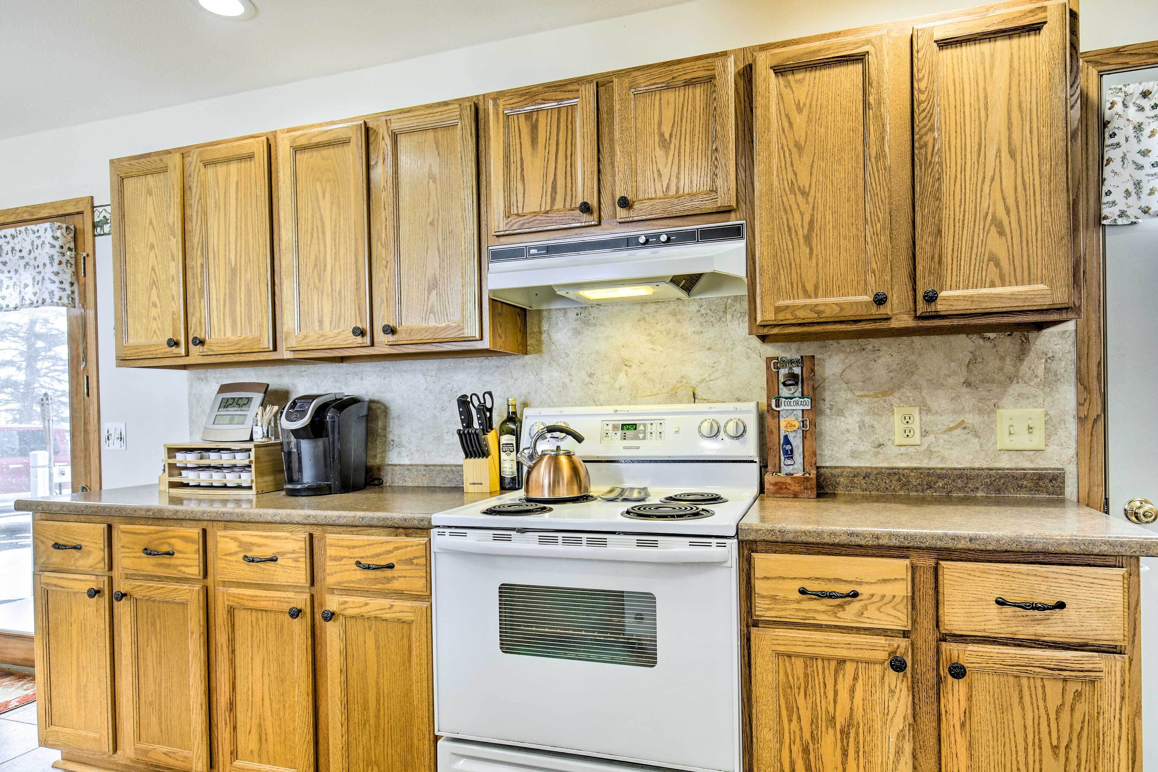 A kitchen with wooden cabinets, a white stove, and various kitchen items on the counter.