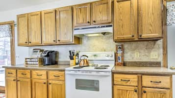 A kitchen with wooden cabinets, a white stove, and various kitchen items on the counter.