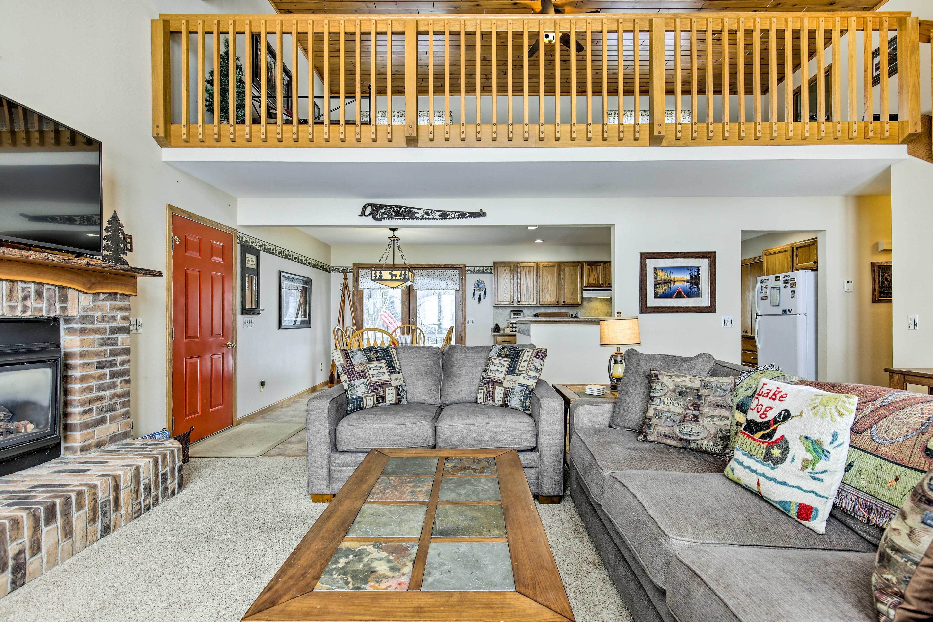 A spacious living room with a fireplace, a grey sofa set, and a wooden coffee table.