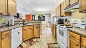 Una cocina con armarios de madera, lavavajillas, estufa y refrigerador.