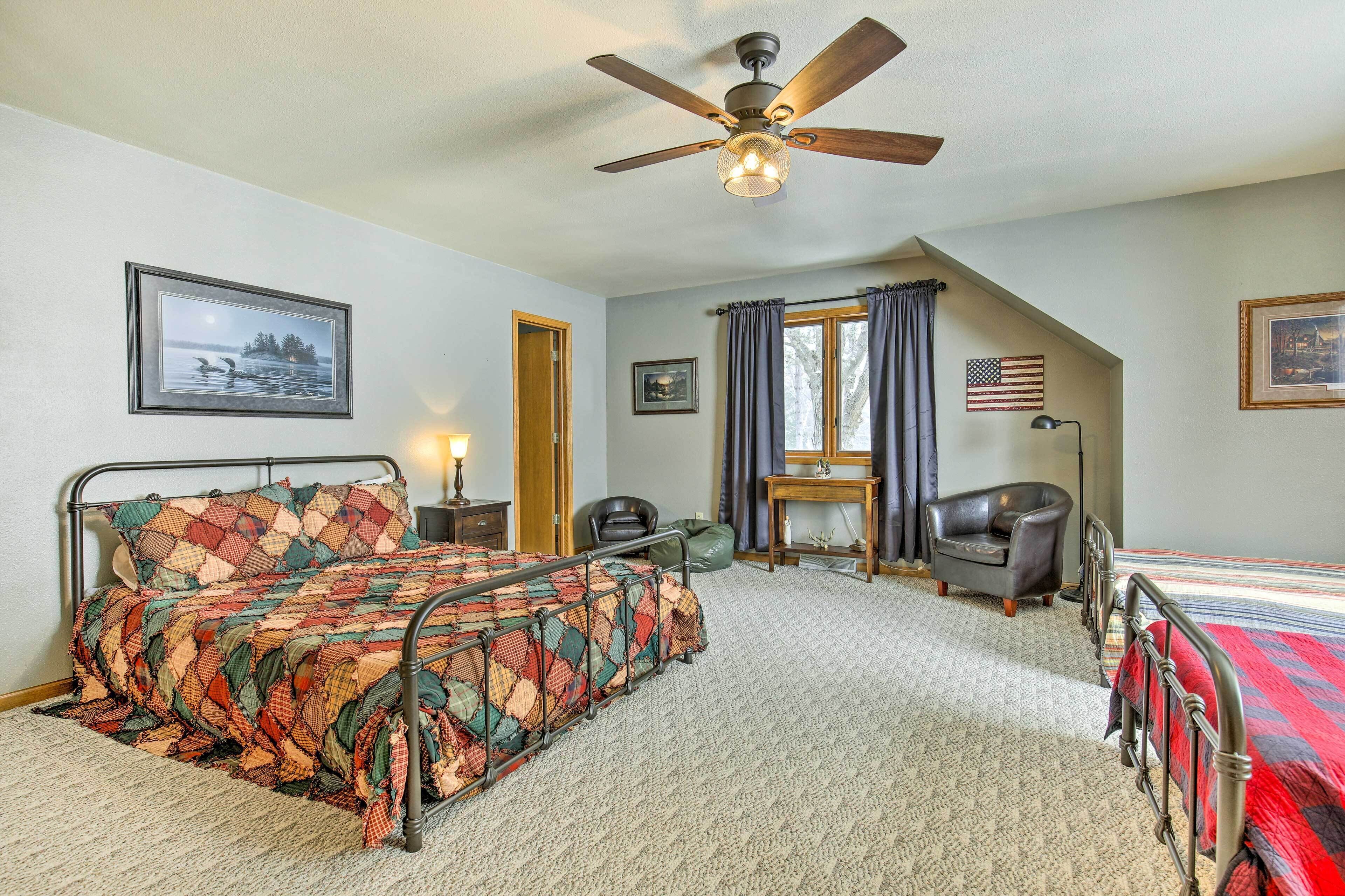 Une chambre à coucher avec un lit, un ventilateur de plafond, une fenêtre avec des rideaux, un drapeau américain et un tableau encadré accroché au mur.