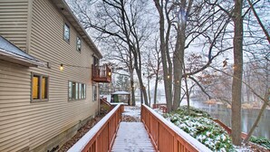 A wooden deck leading to a house with a covered porch and a view of a lake. - Lake Access, Hot Tub & 2 Decks: Ortonville Retreat (Ortonville)