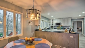 A modern kitchen with a central island, wooden cabinetry, and a dining area with a round table and placemats. - Lake Access, Hot Tub & 2 Decks: Ortonville Retreat (Ortonville)