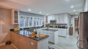 A modern kitchen with white cabinetry, a central island, and a stainless steel refrigerator. - Lake Access, Hot Tub & 2 Decks: Ortonville Retreat (Ortonville)