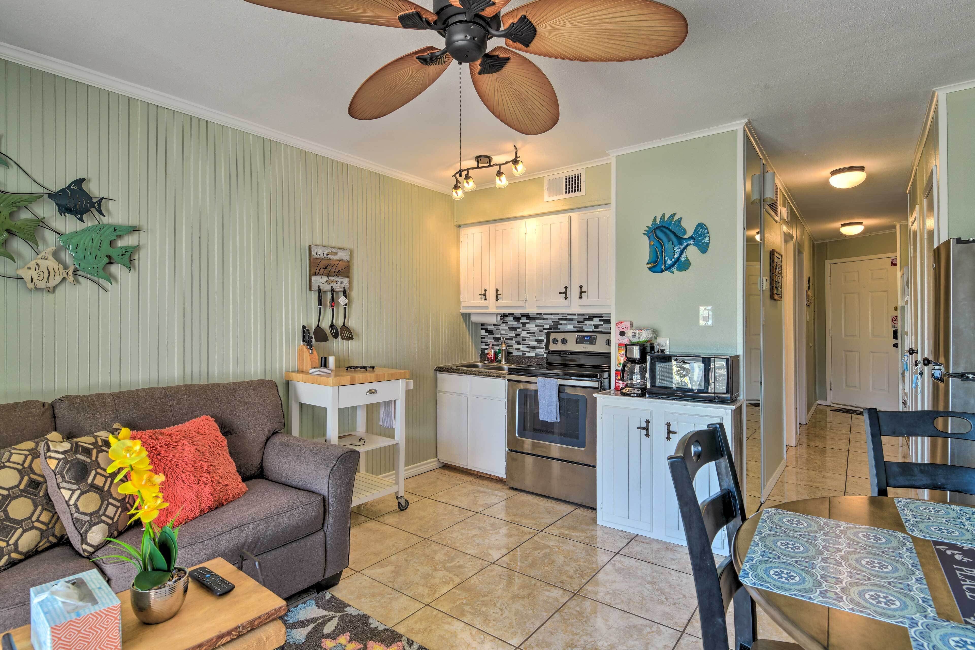 A compact living space with a kitchenette, a dining area, and a sofa with decorative pillows.