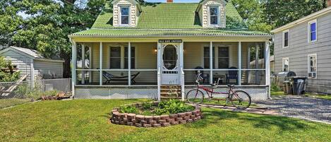 Una casa de dos pisos con un porche, un jardín pequeño y una bicicleta.