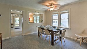 Comedor con una mesa dispuesta para seis personas, ventilador de techo y vista a la cocina a través de una puerta abierta.