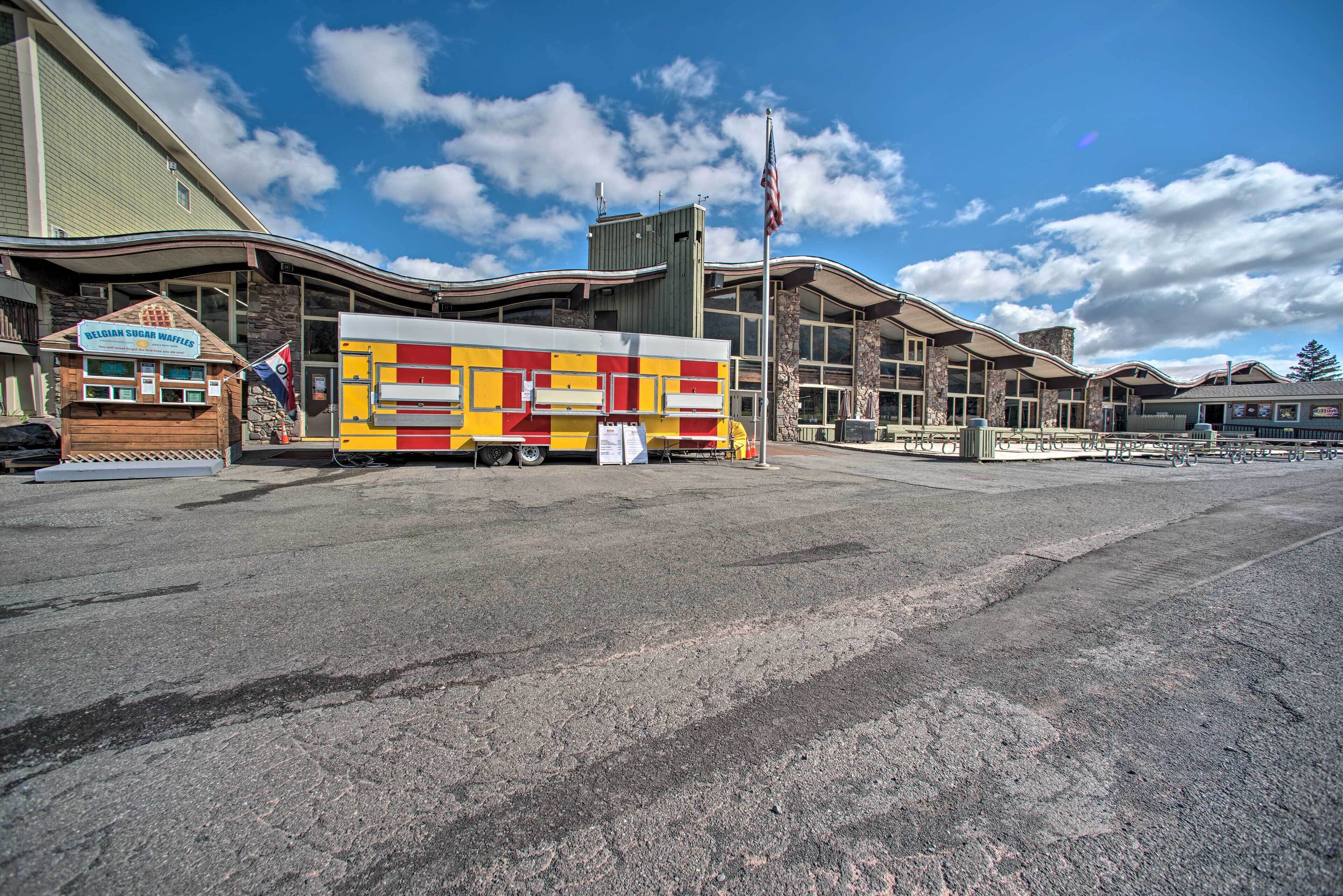 A food truck with a red and yellow design parked in front of a building with a flag.