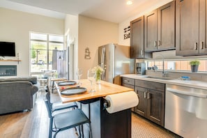 A modern kitchen with dark wooden cabinets, a stainless steel refrigerator, and a wooden island with bar stools. - Steps to Conquest Ski Lift: Granby Home w/ Grill (Granby)