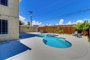 En baghave med swimmingpool, træhegn og terrasse med udendørs møbler.