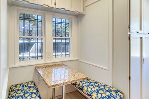 A kitchen with a window, a countertop, and two bench seats with a floral pattern.
