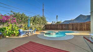 Un jardin avec une piscine, une terrasse en bois et un espace patio aménagé avec des chaises et une table.