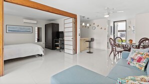 Ein modernes Wohnzimmer mit einer Couch, einem Essbereich mit Stühlen, einer Küchenzeile und einem Schlafzimmer mit einem Bett.