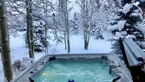 Ein Whirlpool, umgeben von schneebedeckten Bäumen.