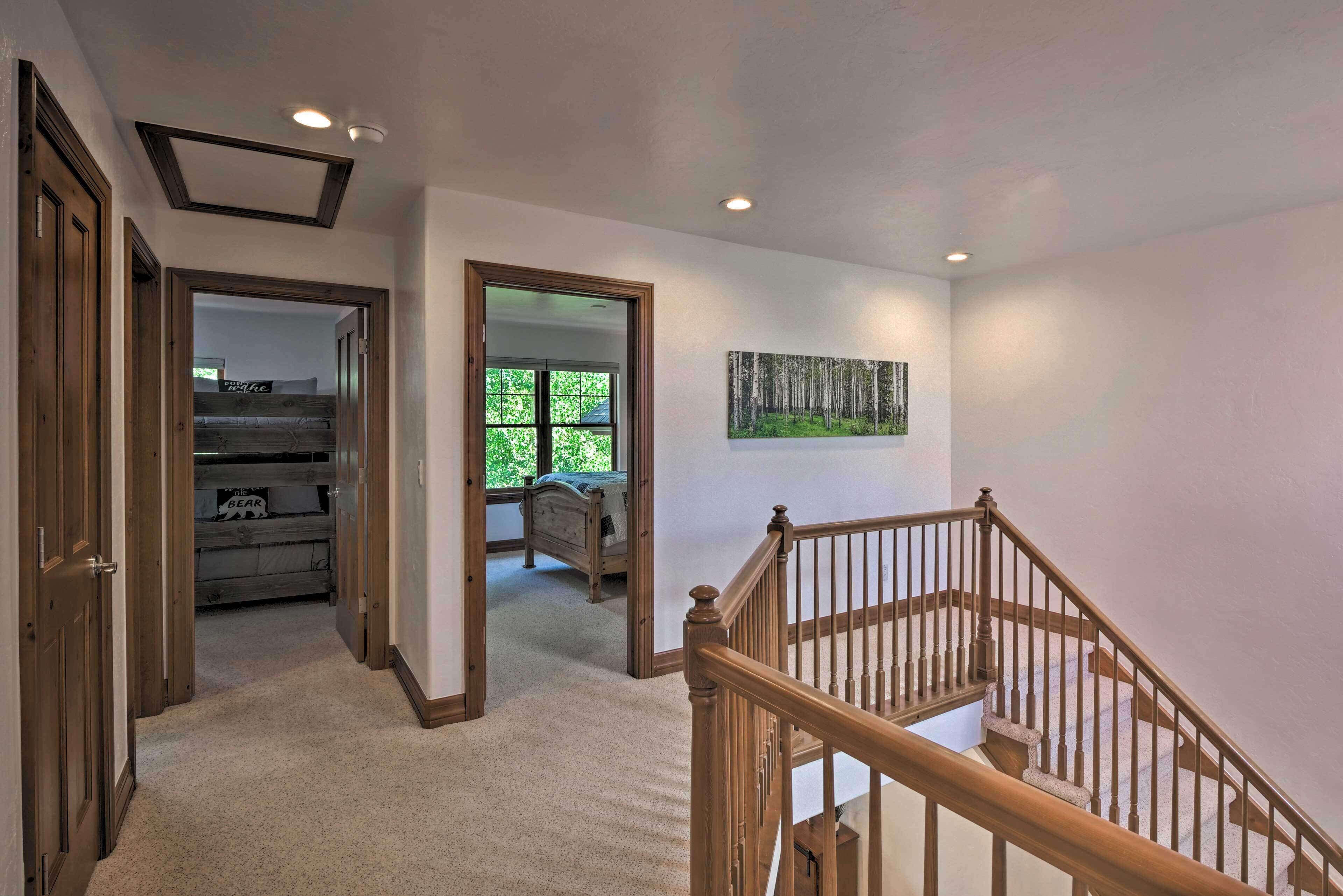 A hallway with a wooden staircase, carpeted floors, and a painting on the wall.