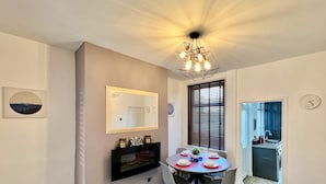 A dining area with a round table, chairs, a mirror, and a ceiling light fixture.