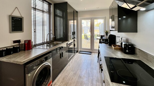 A modern kitchen with a built-in washer, a sink, and a stove.