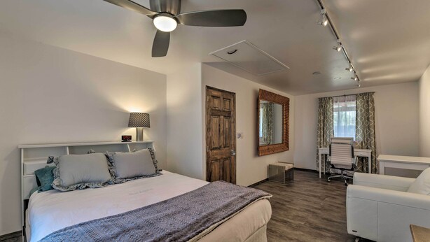 Une chambre d’hôtel équipée d’un lit, d’un bureau, d’une chaise, d’un ventilateur de plafond et d’un miroir.