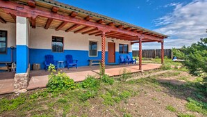 Une maison avec un patio couvert, des chaises bleues et une clôture en bois.