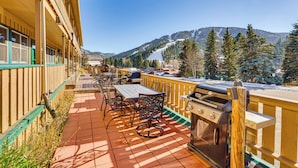 A patio with outdoor seating, a grill, and a view of snow-covered mountains.