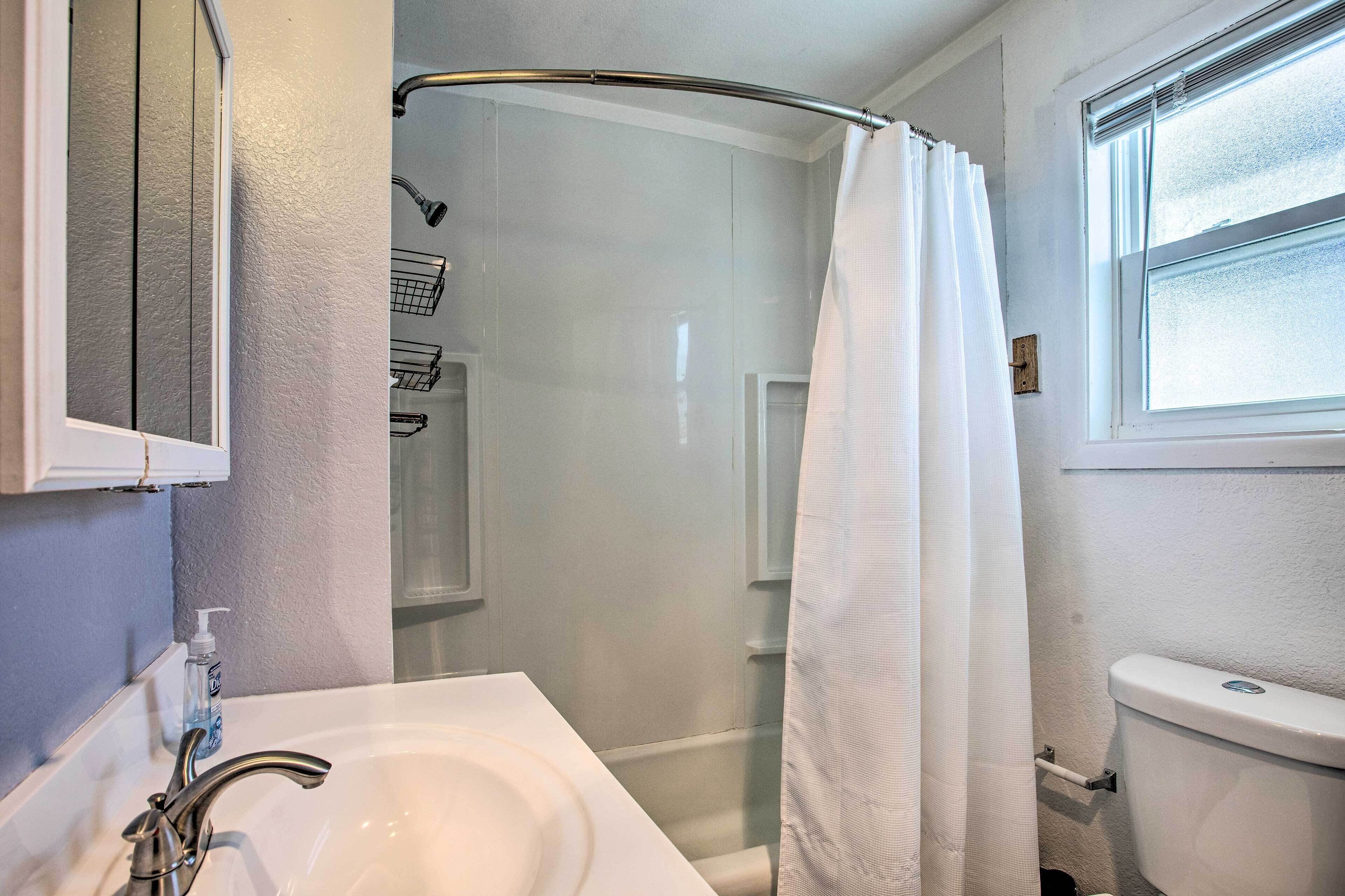 A bathroom with a white sink, a shower with a glass door, and a toilet.