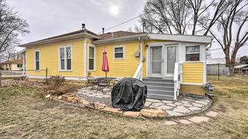 A yellow house with a covered patio, a small deck, and a covered grill.