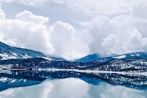 A serene lake surrounded by snow-covered mountains and dense forests. - Walk to Frisco Main St: Townhome Steps to Trail! (Frisco)