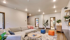 Un salon moderne avec un canapé d’angle, une table basse ronde et une grande plante.