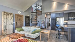 A modern kitchen with a stainless steel refrigerator, a microwave, and a bar area. There is a staircase leading to an upper level. - Lake Pagosa Home w/ Hot Tub & Mtn/lake Views! (Pagosa Springs)