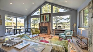 A spacious living room with a fireplace, large windows, and a view of the outdoors. - Lake Pagosa Home w/ Hot Tub & Mtn/lake Views! (Pagosa Springs)