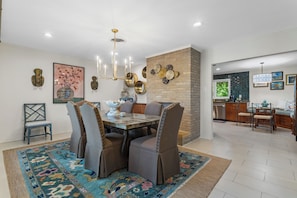 A dining area with a large table, chairs, and a chandelier. - Live Oaks & Marina Views! Ocean Springs Home (Ocean Springs)