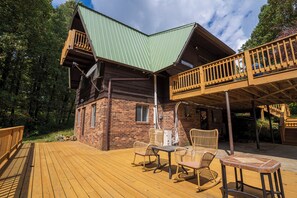 Een houten chalet met terras, buitenmeubels en een groen dak.
