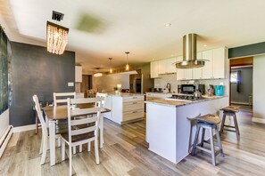 Une cuisine moderne dotée d’un îlot central, de meubles blancs et d’un lustre.