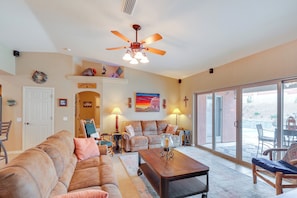 Relax in a spacious living area with a high ceiling fan and a large window offering a view of the outdoors.