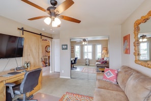 Relax in a spacious living area with a large flat-screen TV, comfortable couch, and a wooden desk for work or leisure.