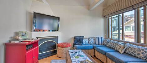 Una sala de estar con chimenea, un armario rojo, un sofá azul y ventanas amplias.