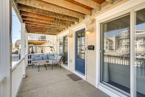 A covered porch with a seating area, a sliding glass door, and a view of neighboring houses.