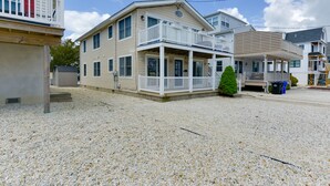 Ein Strandgrundstück mit einem zweistöckigen Haus, einer Veranda und einem kleinen Garten.