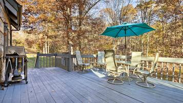 A wooden deck with outdoor furniture and a grill.