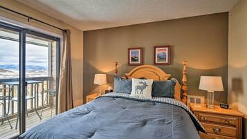 A bedroom with a large bed, two bedside tables with lamps, a wooden headboard, and two framed pictures on the wall.