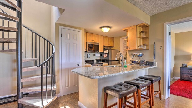 A kitchen with a central island, wooden cabinets, and a stainless steel refrigerator. - Walk to Ski Lift: Mtn-view Granby Ranch Condo (Granby)